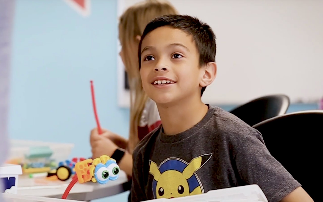 A student smiles while learning in a STEAM lab.